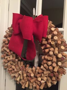 a wreath made out of wine corks with a red bow on the front door