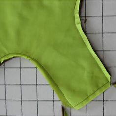 a green piece of cloth sitting on top of a white tile floor next to a ruler