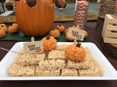 rice krispy treats are displayed on a table with pumpkins and candy sticks in the background