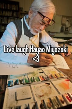 an older man sitting at a table with paint and watercolors