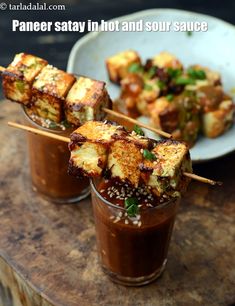 tofu skewers are served in small cups with chopsticks on the side