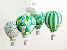 three hot air balloons are hanging from the ceiling and one is painted green, white and blue