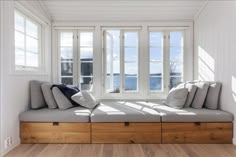 a window seat in the corner of a room with wooden flooring and white walls