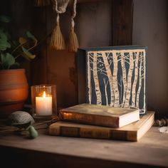 an open book sitting on top of a wooden table next to a candle and some books