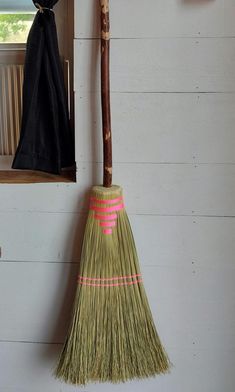 a broom hanging on the wall next to a window