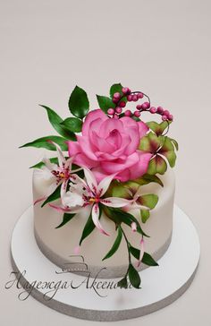 a white cake with pink flowers and green leaves