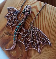 two metal dragon pendants sitting on top of a wooden table