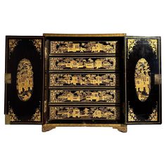 A fine Chinese Export black lacquered gilt painted table top cabinet for jewelry or collectibles, mid 19th century, circa 1850, China for the English or American market. The stately cabinet of typical form, supported on bracket feet, and with two doors that open to reveal a series of five drawers. Black lacquer covers the surfaces, providing the background for intricately gilt painted details. The two doors feature recessed panels painted in gilt with objects from the "Hundred Antiques" interspe Painted Table Top, Chinese Furniture, Wooden Dresser, Jewelry Cabinet, Chinese Export, Painted Paneling, Black Lacquer, Painted Table, Art Furniture