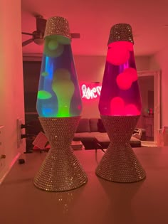 two vases that are sitting on top of a table in front of a neon sign