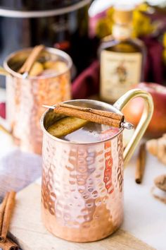 two copper mugs filled with cinnamon and apple cider