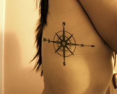 a woman's shoulder with a compass tattoo on her left side ribcage