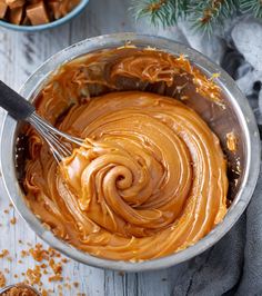 a bowl filled with peanut butter and topped with a whisk