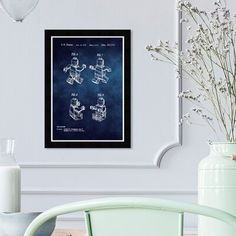 a chair and vase with flowers in front of a framed blueprint poster on the wall