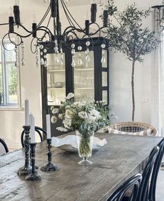 a wooden table topped with a vase filled with flowers next to a tall candle holder