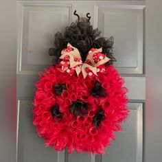 a red and black wreath hanging on the front door