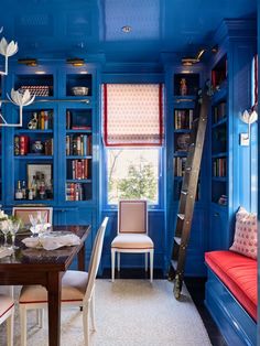 a dining room with blue walls and built in bookshelves