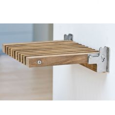 a wooden shelf mounted to the side of a wall with two metal brackets on it