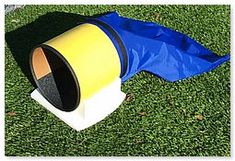 a yellow and blue cone sitting on top of a green field next to a bag