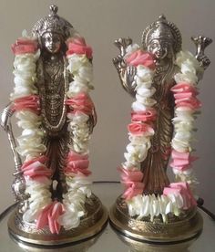 two silver figurines with pink and white flowers on them