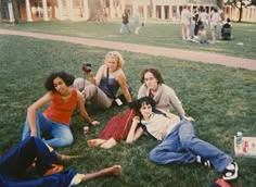 group of young people sitting on the grass in front of a building with one person taking a photo