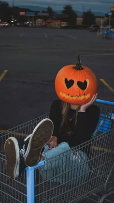 a woman sitting in a shopping cart with a pumpkin on her head and eyes drawn out