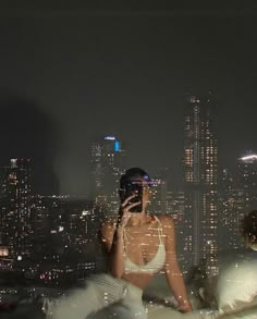 a woman taking a selfie in front of the city at night with her cell phone