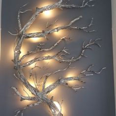 a wall sculpture with lights on it in the shape of a tree branch and branches