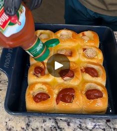 hot dog buns with ketchup and mustard being poured on them in a baking pan