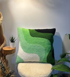 a green pillow sitting on top of a white chair next to a potted plant