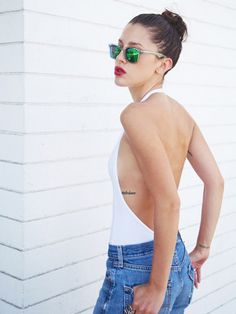 a woman with her back to the camera wearing high waist jeans and green mirrored sunglasses