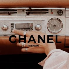 a woman is touching the radio button on her car's dash board, which reads chanel fashion