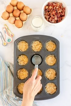 an overhead view of a muffin tin with eggs and other ingredients on the side