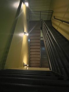 stairs leading up to the top of a building with lights on each handrails