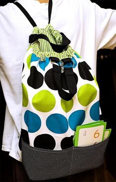 a child wearing a polka dot backpack with a book in it's back pocket