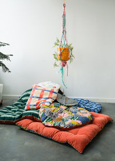 a pile of blankets sitting on top of a floor next to a potted plant