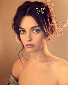 a woman with flowers in her hair is wearing a dress and looking at the camera