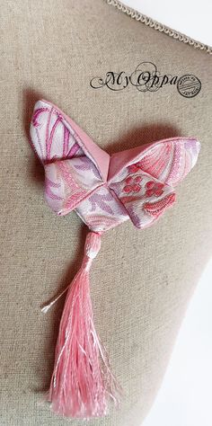 a pink and white scarf with tassels on it sitting on a mannequin