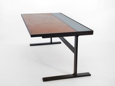 a black table with a wooden top and metal legs on a white background in an empty room