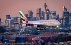 an airplane is taking off from the runway in front of a cityscape at dusk