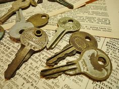 several old keys are laying on top of an open book with pages in the background