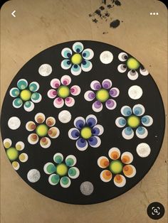 a black plate with multicolored flowers and dots on the top, sitting on a table