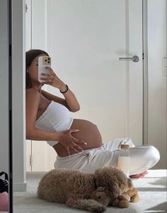 a pregnant woman taking a selfie with her cell phone while laying on the floor