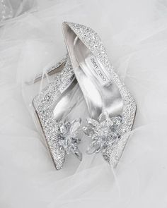 a pair of silver high heel shoes with bows on the toes and heels covered in crystal stones