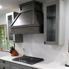 a stove top oven sitting inside of a kitchen next to a counter with knives and utensils on it