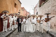 a group of people standing next to each other holding guitars and wearing sombreros