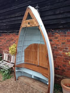 a wooden bench sitting in front of a building with a canoe shaped seat on it's side