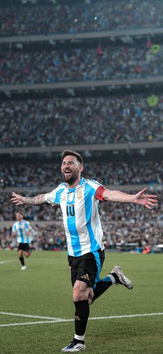 a man is running on the soccer field with his arms out to catch the ball