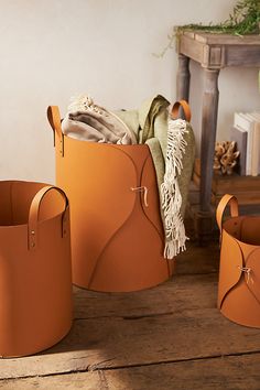 three orange buckets sitting on top of a wooden floor