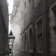 a street light in the middle of an alley way with stone buildings on both sides