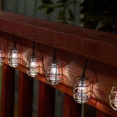 five lights are hanging on the side of a wooden rail